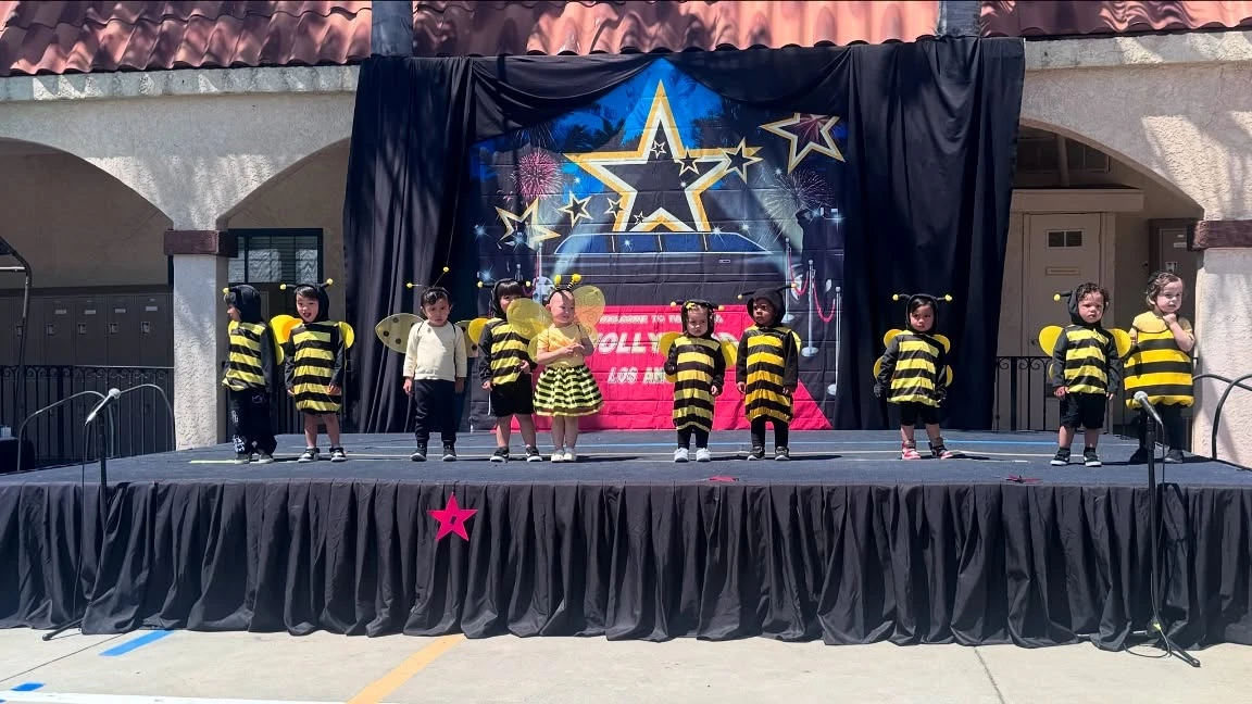 Young Page Academy students performing on stage in bee costumes