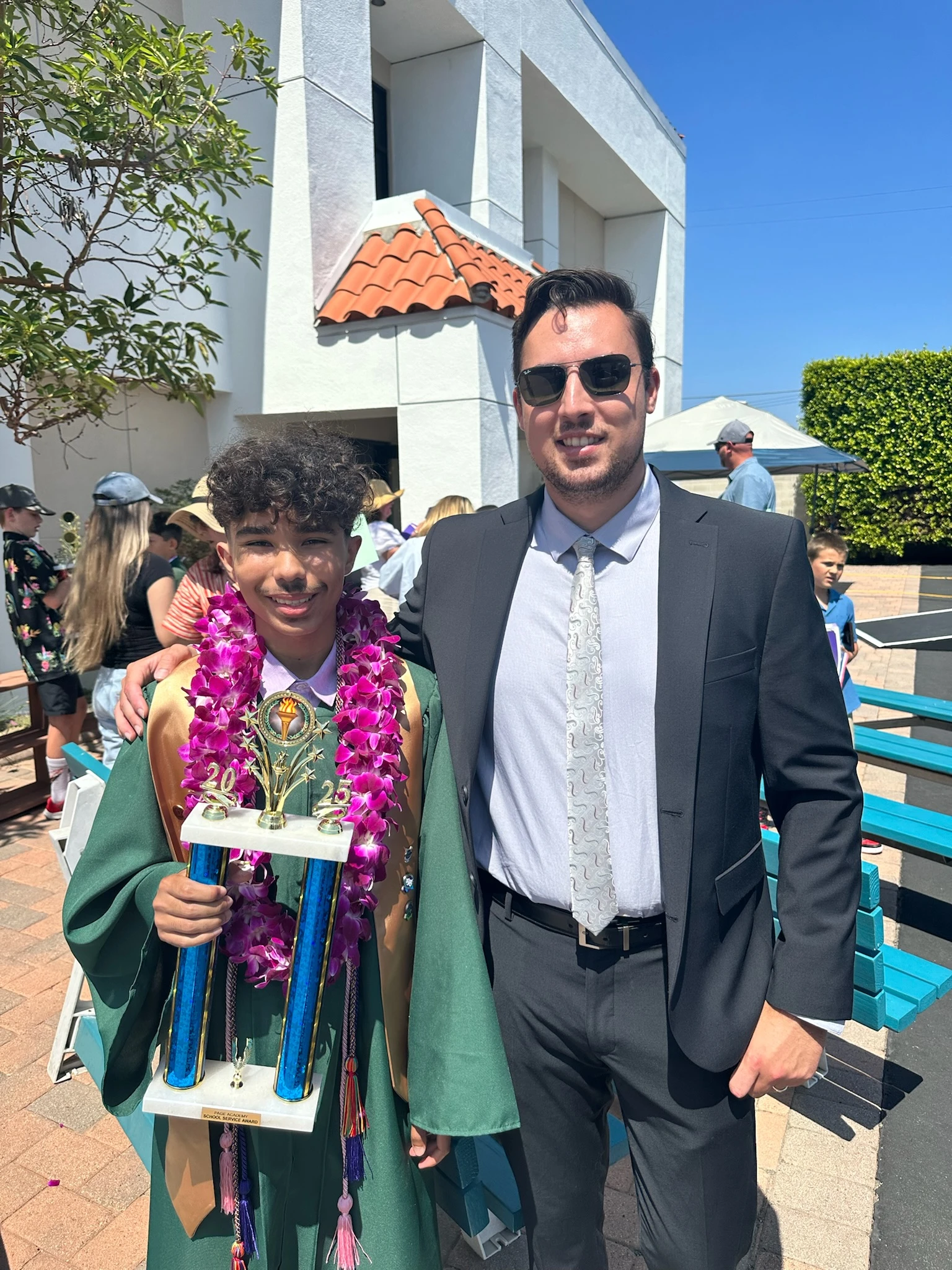 Page Academy graduate in a cap and gown holding a trophy