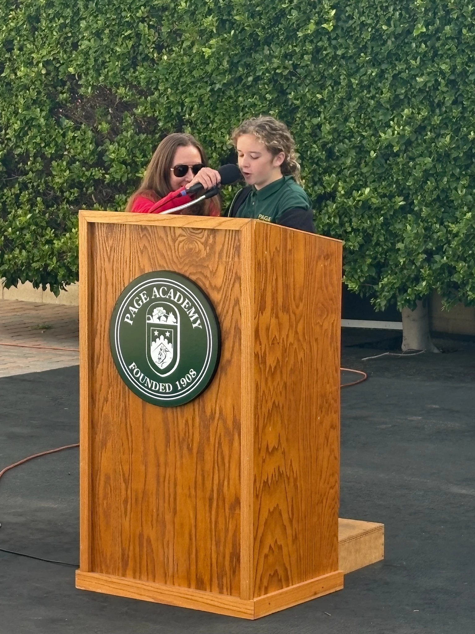 Two Page Academy students speaking together at the school podium