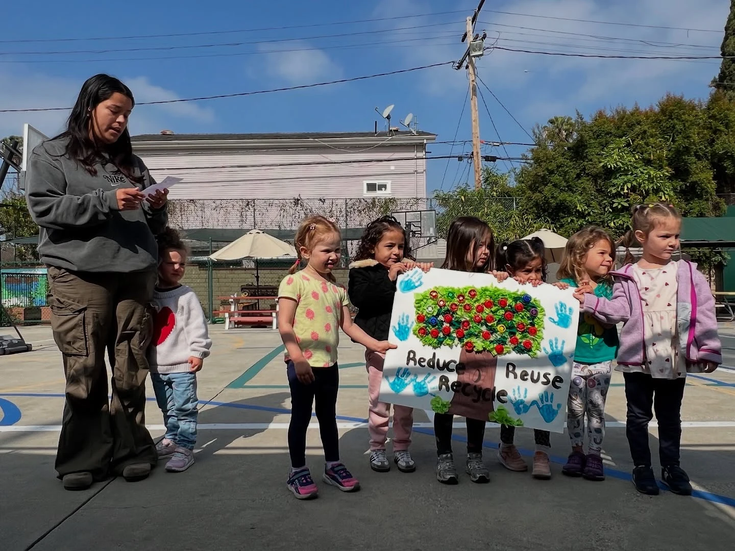 Young Page Academy students holding up a class poster with their teacher